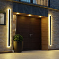 Slim black vertical outdoor wall light casting a warm glow