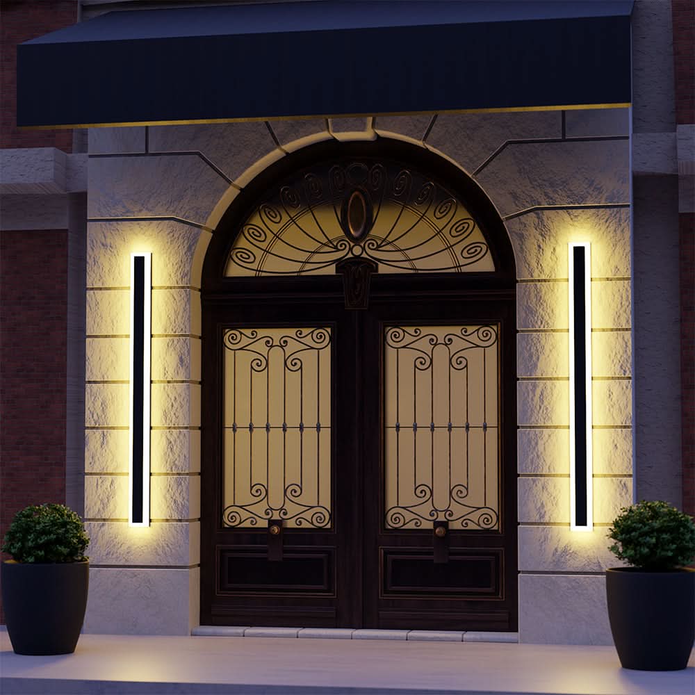 Slim black vertical outdoor wall light casting a warm glow
