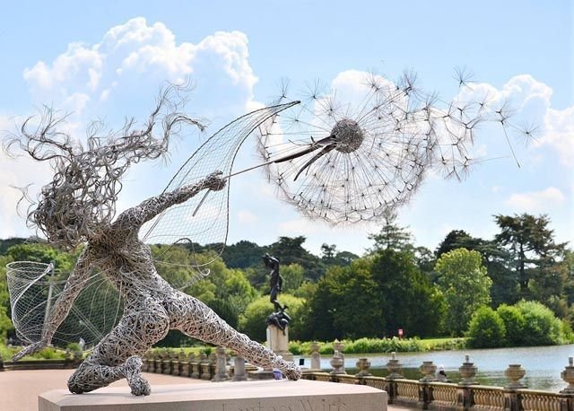 Black metal garden sculpture with fairy silhouettes and dandelion seed heads