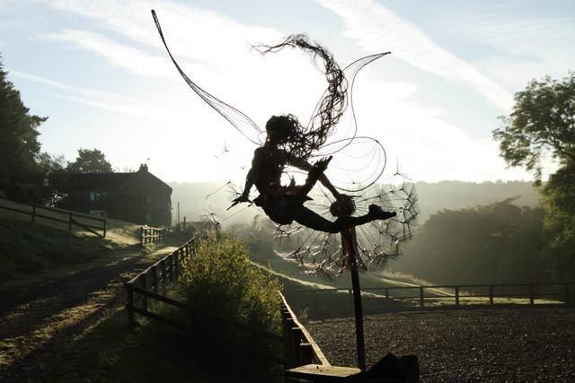 Black metal garden sculpture with fairy silhouettes and dandelion seed heads