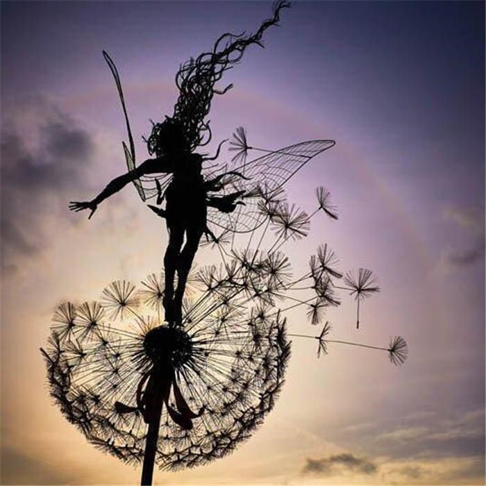 Black metal garden sculpture with fairy silhouettes and dandelion seed heads