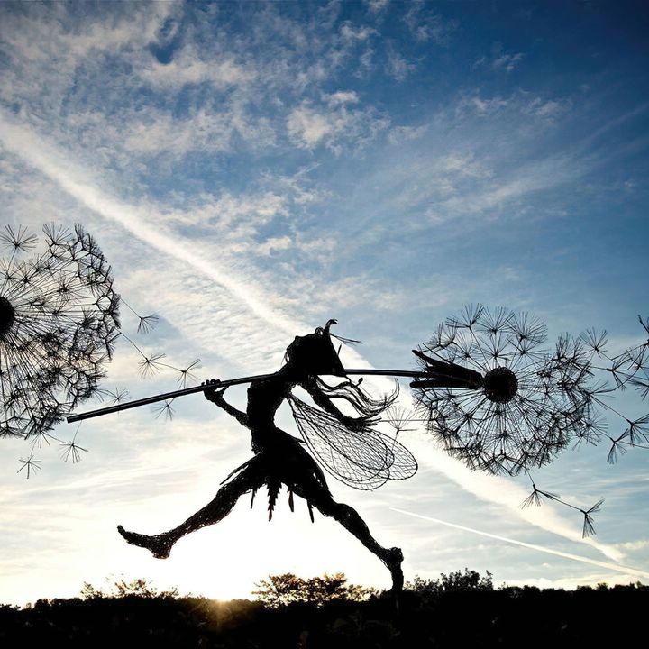 Black metal garden sculpture with fairy silhouettes and dandelion seed heads