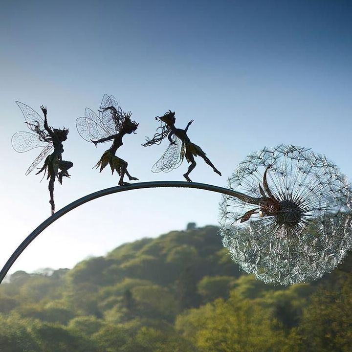 Black metal garden sculpture with fairy silhouettes and dandelion seed heads
