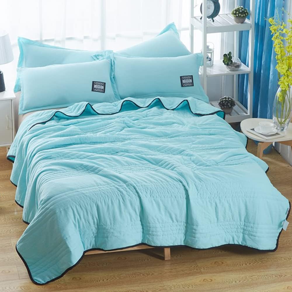 Quilted summer blanket draped over a bed with dark contrast edging