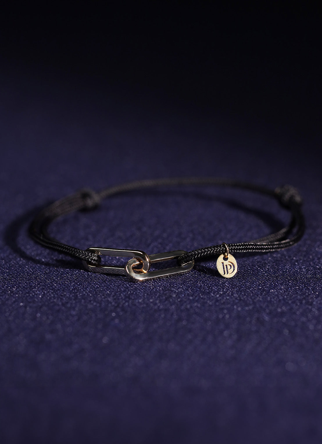 Black cord bracelet with a yellow-gold clasp