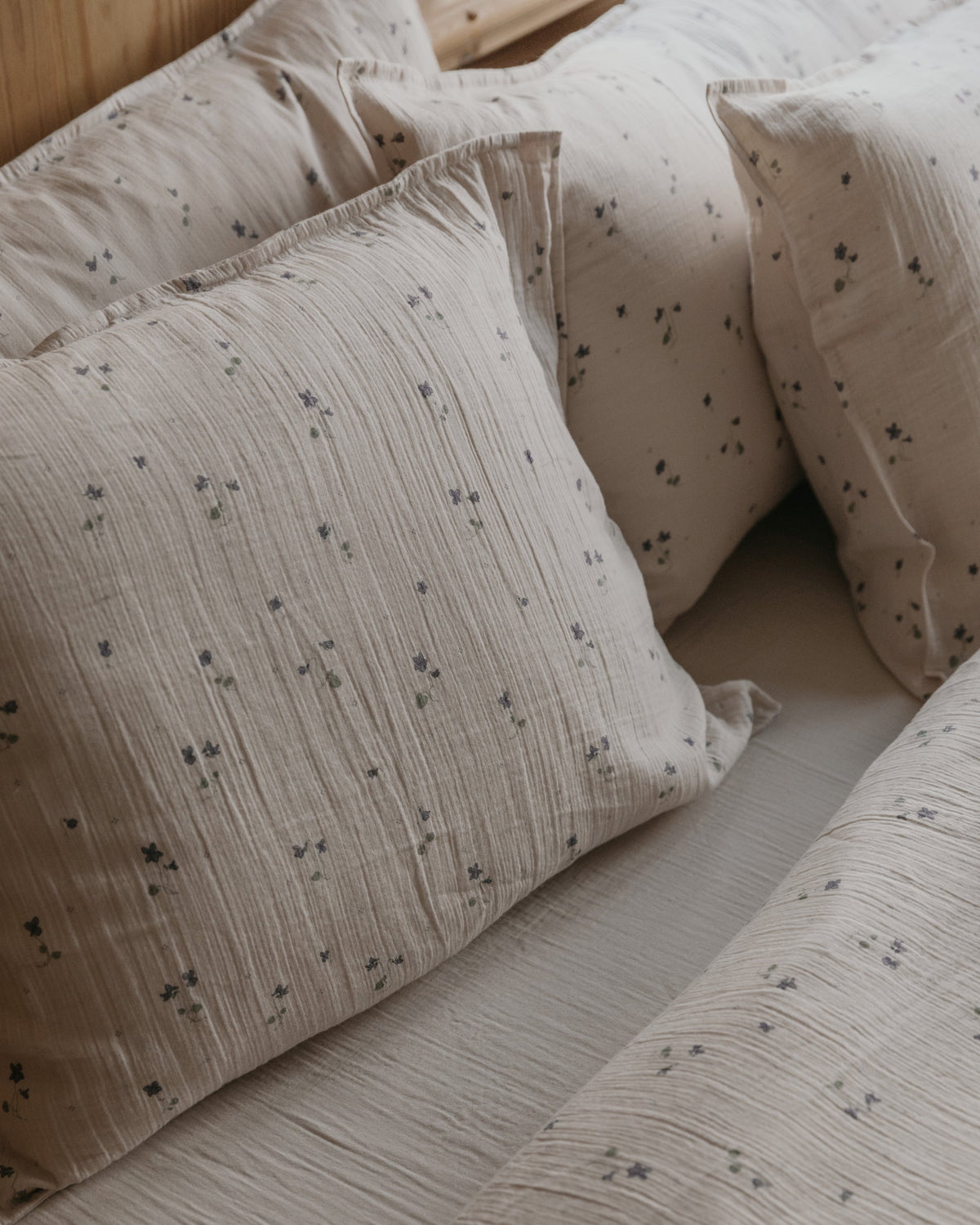 Beige muslin pillowcase with small purple floral pattern and gathered texture