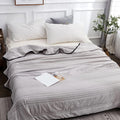 Quilted summer blanket draped over a bed with dark contrast edging