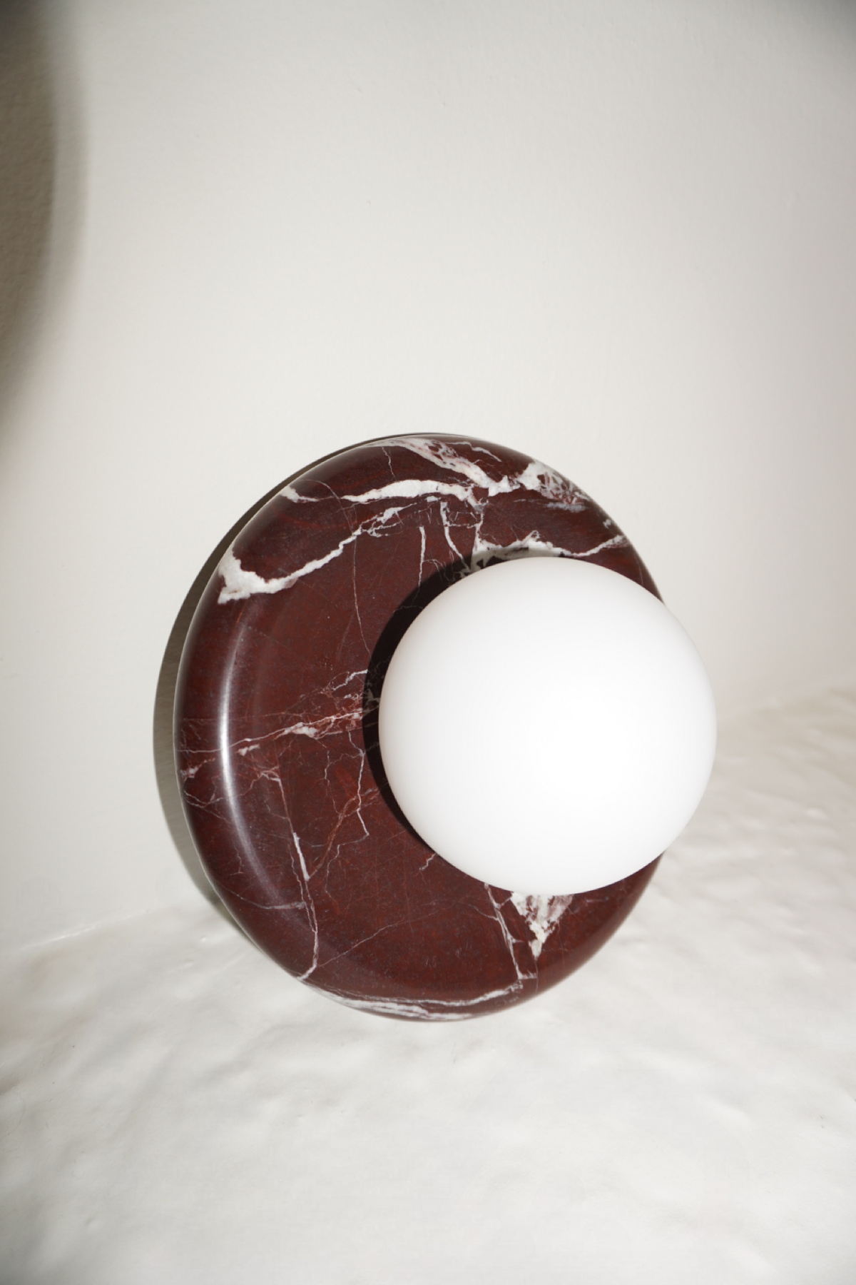 Circular marble wall sconce with a smooth globe shade