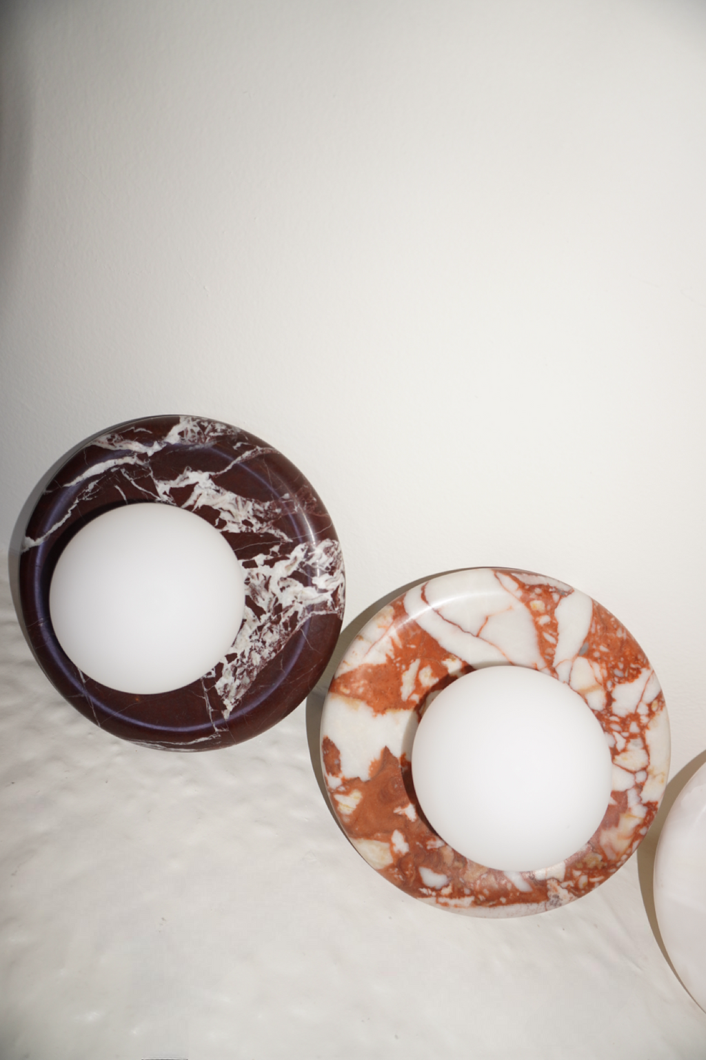 Circular marble wall sconce with a smooth globe shade