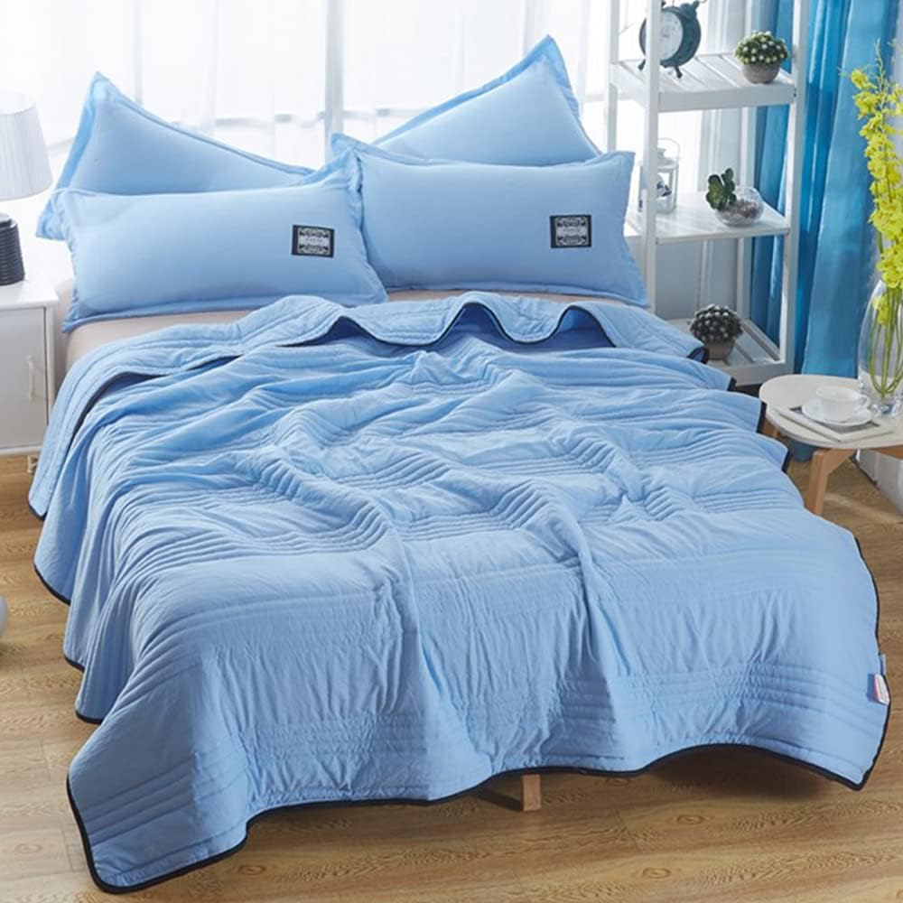 Quilted summer blanket draped over a bed with dark contrast edging