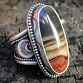 Silver ring with an elongated oval banded stone and beaded decorative setting