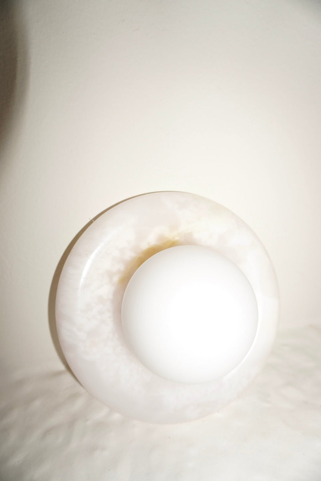 Circular marble wall sconce with a smooth globe shade