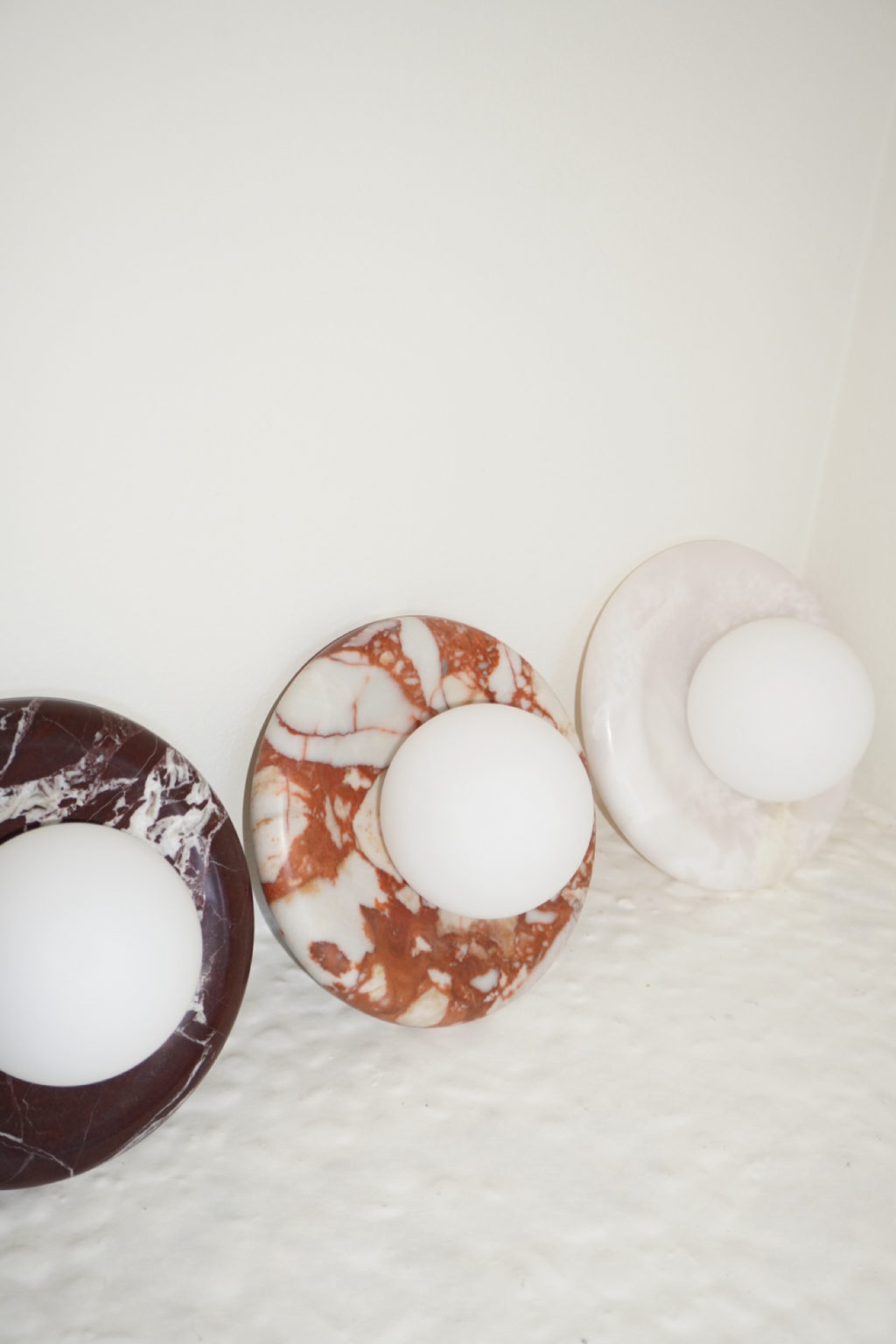 Circular marble wall sconce with a smooth globe shade