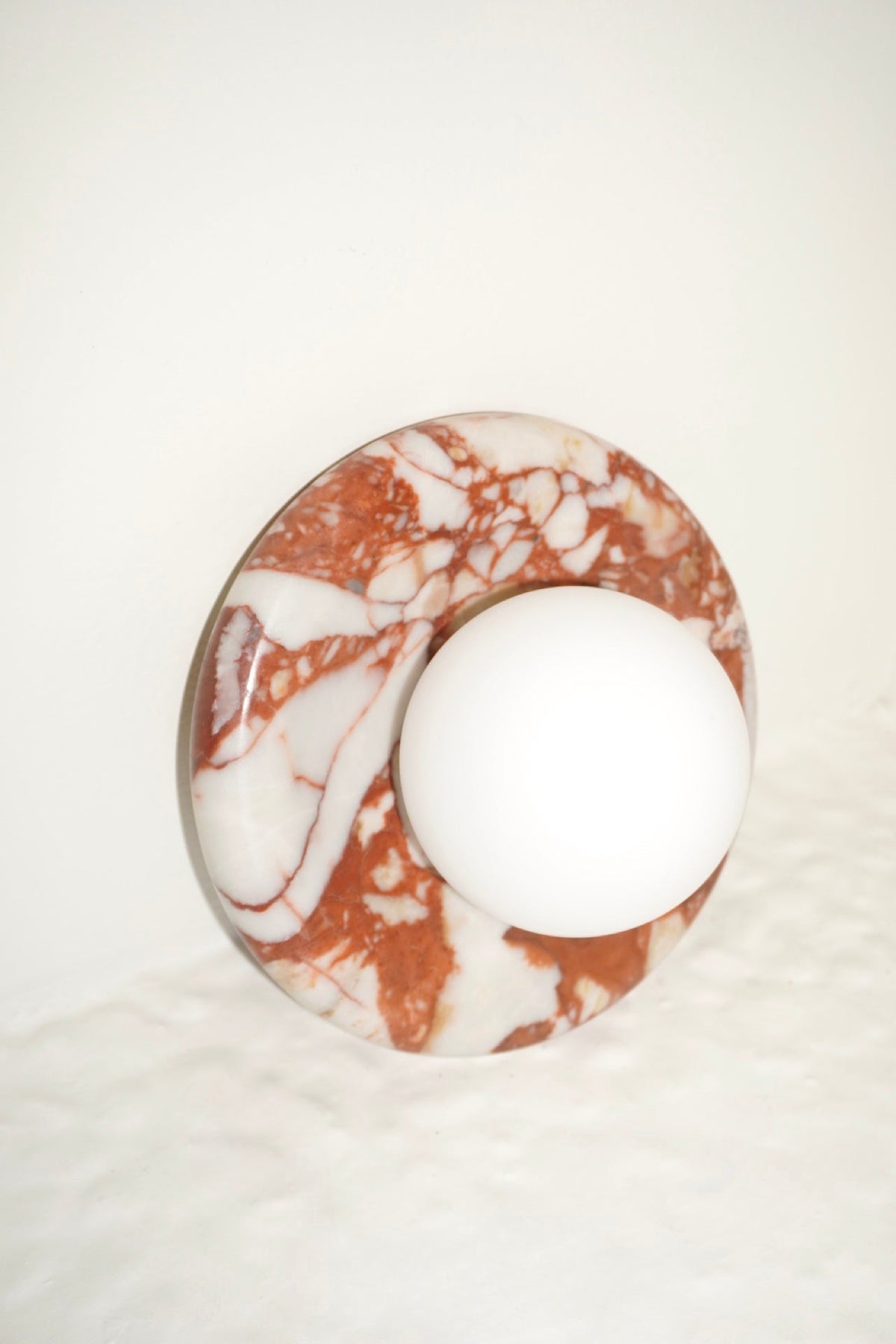 Circular marble wall sconce with a smooth globe shade