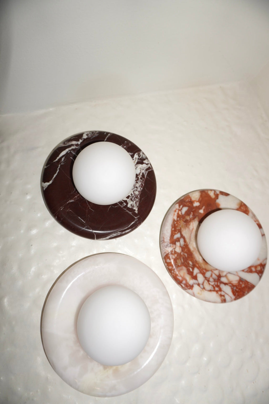 Circular marble wall sconce with a smooth globe shade