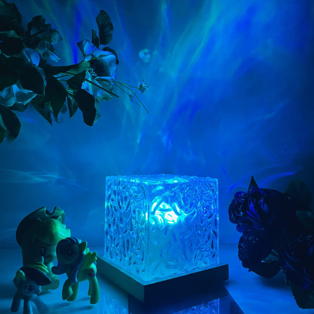 Textured clear cube table lamp glowing with colourful aurora effect light