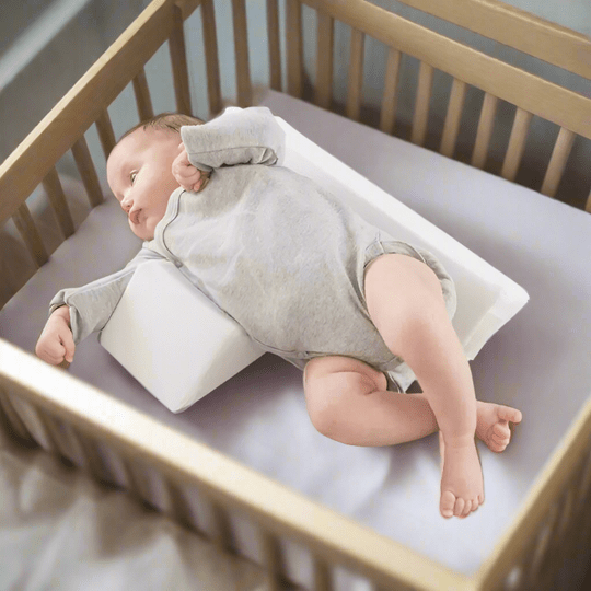Baby positioning pillow with raised side supports in a cot