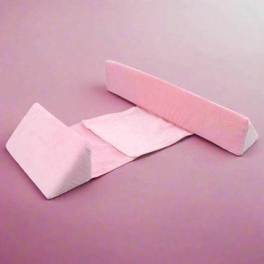 Baby positioning pillow with raised side supports in a cot