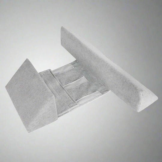 Baby positioning pillow with raised side supports in a cot