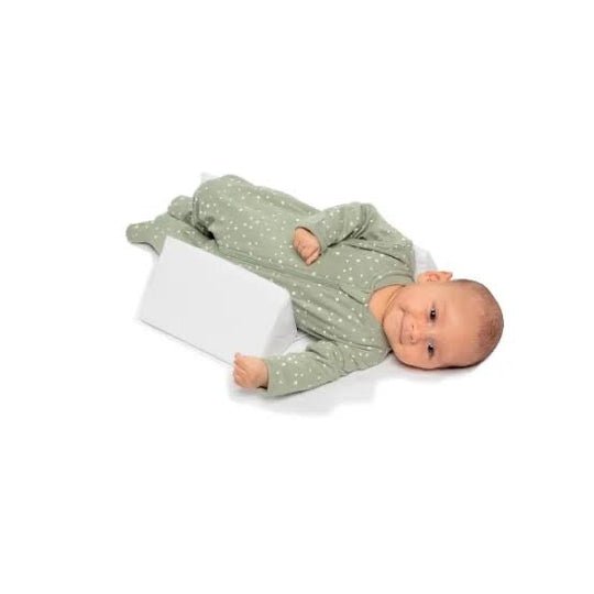 Baby positioning pillow with raised side supports in a cot