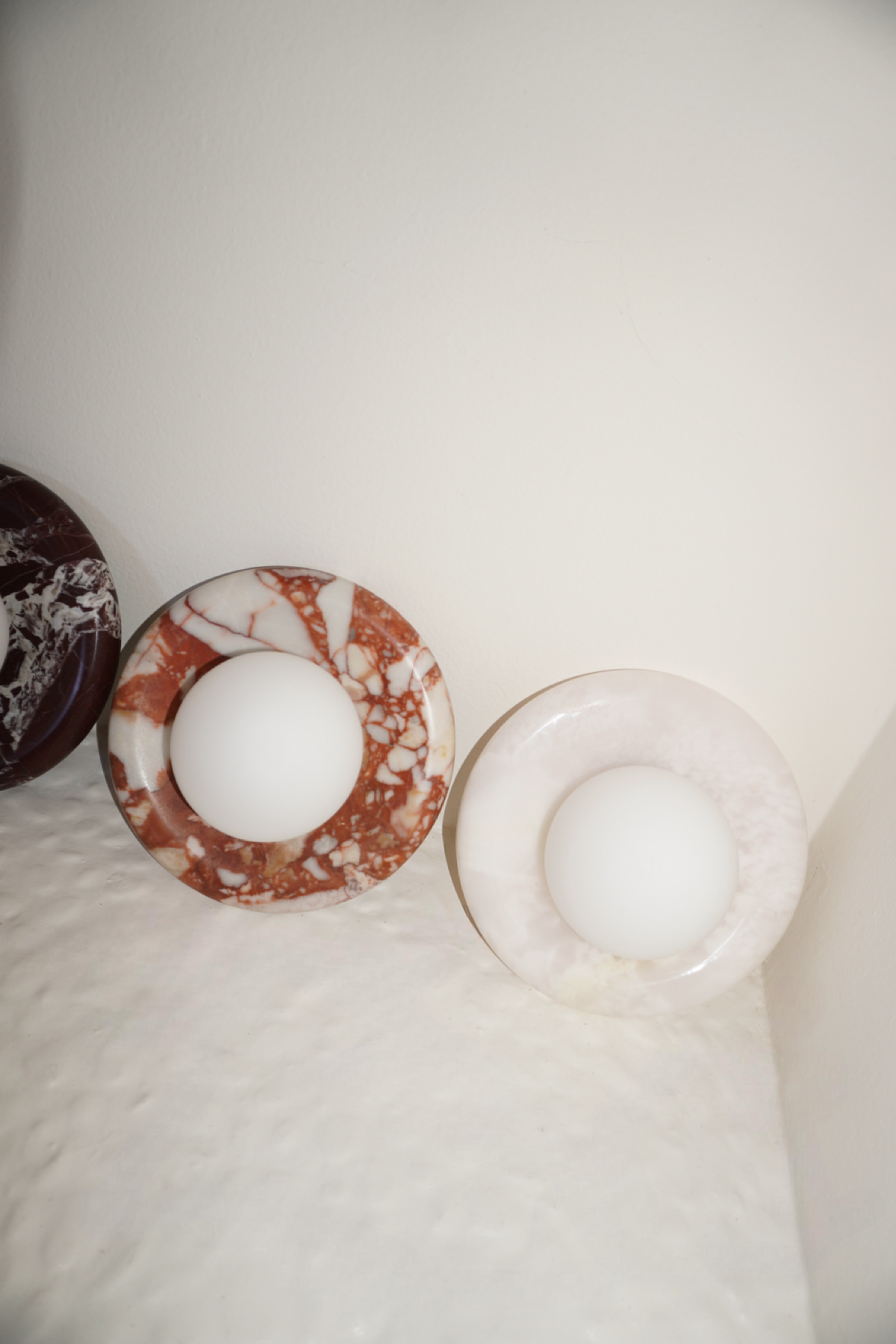 Circular marble wall sconce with a smooth globe shade