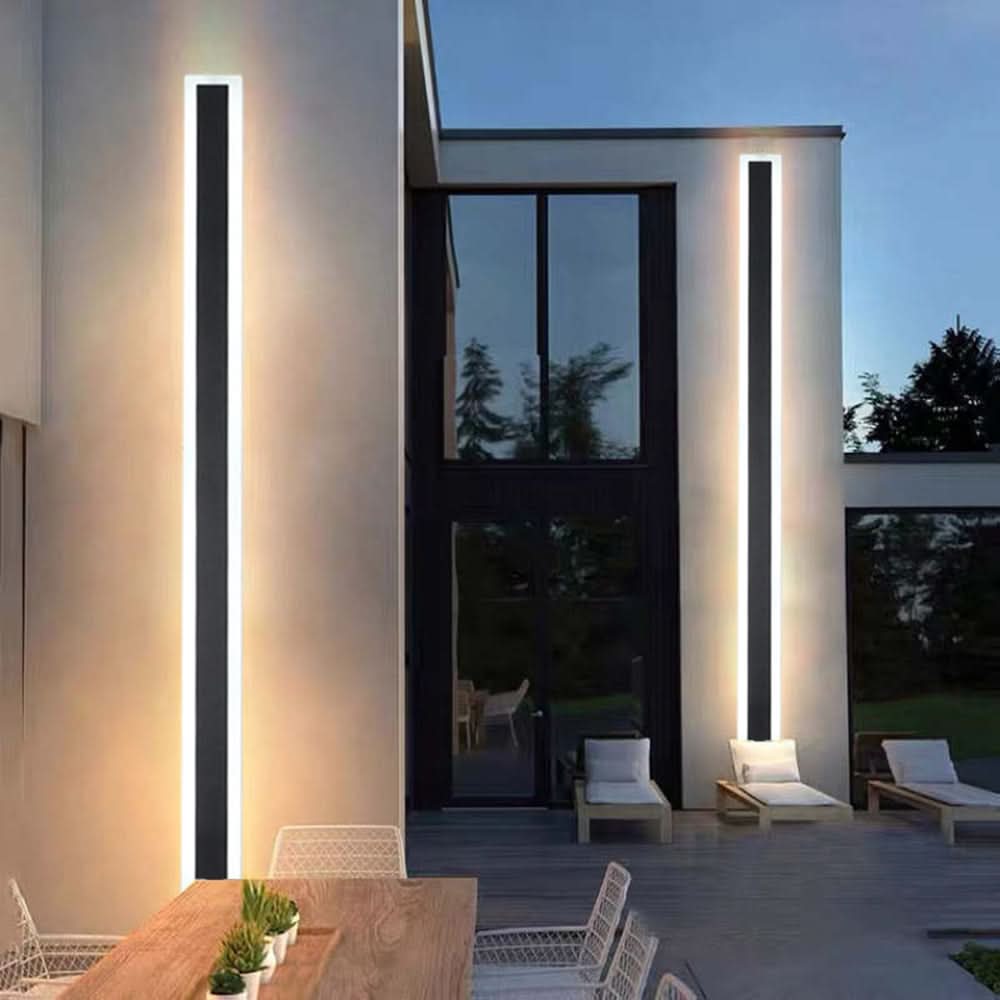 Slim black vertical outdoor wall light casting a warm glow