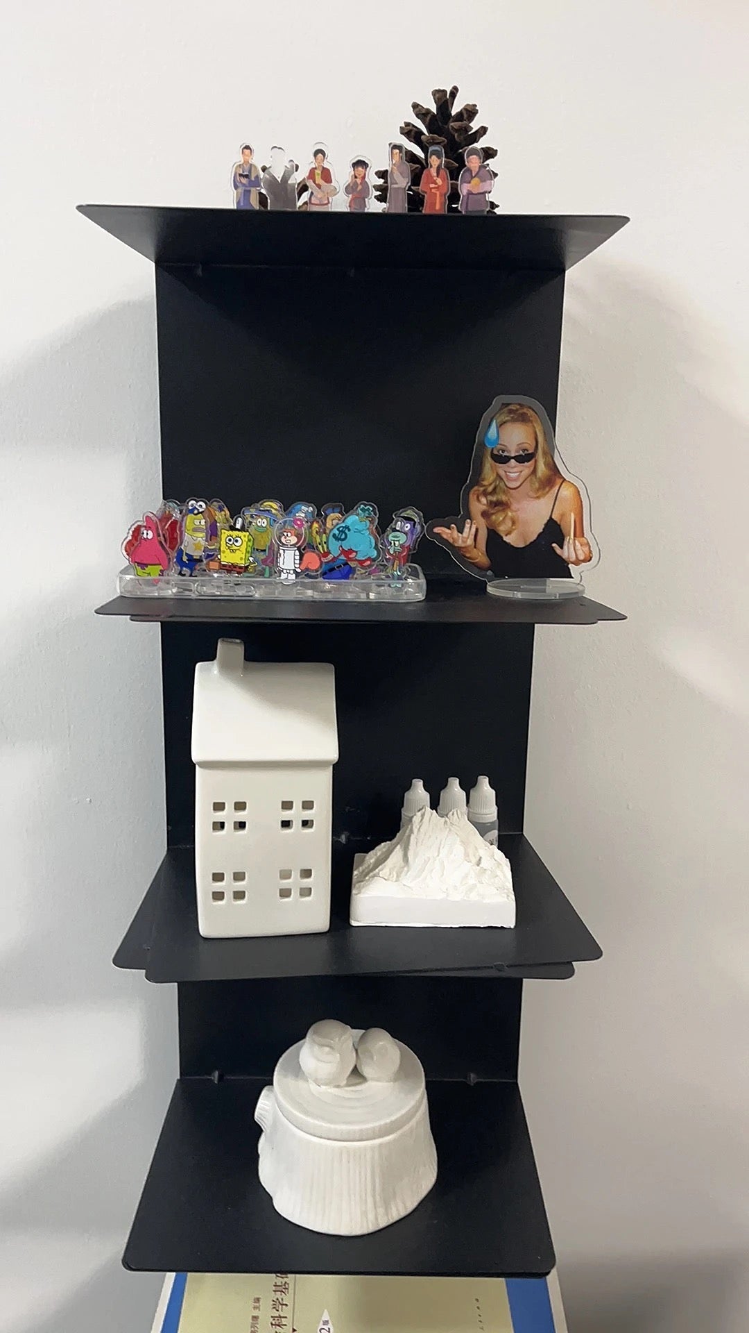 Freestanding tiered metal bookshelf with open shelves and a rectangular base