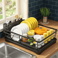 Black dish drying rack with drip tray beside a kitchen sink