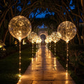 Clear balloons with warm white lights arranged along a garden path and event table