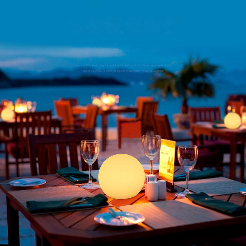 White spherical wireless LED table lamp glowing on a shelf