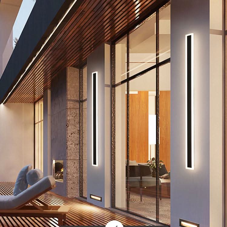Slim black vertical outdoor wall light casting a warm glow