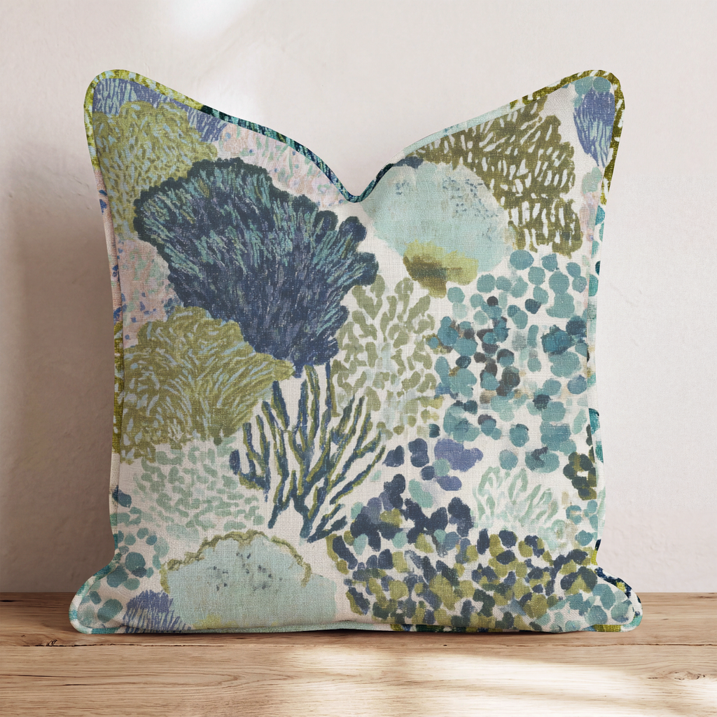 Blue abstract patterned throw pillow with coral-inspired design and piped edges