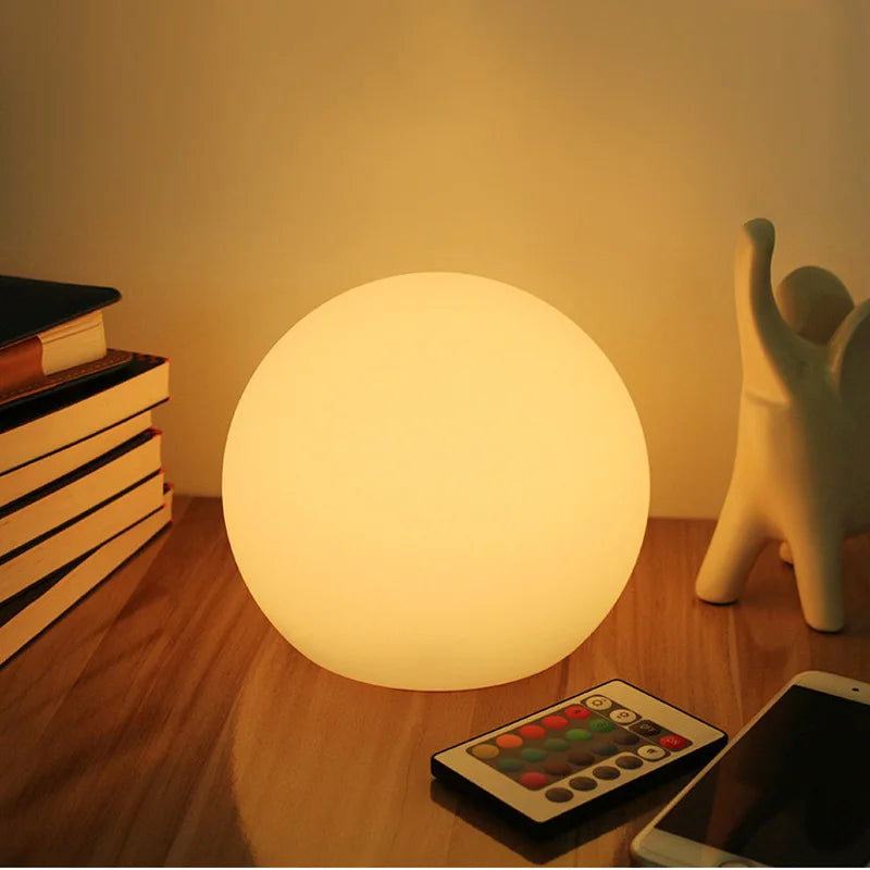 White spherical wireless LED table lamp glowing on a shelf