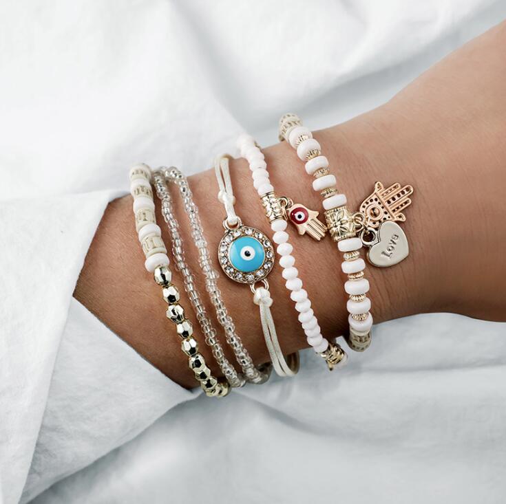 Stacked beaded charm bracelets with eye, hand and heart charms