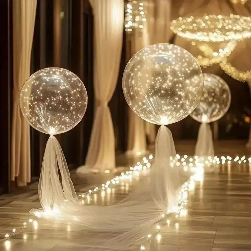 Clear balloons with warm white lights arranged along a garden path and event table
