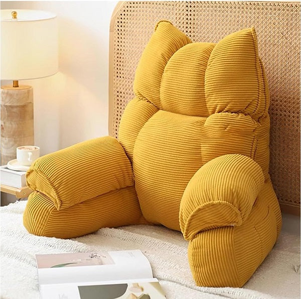 Cushioned bed reading pillow with raised arm supports and ribbed cover