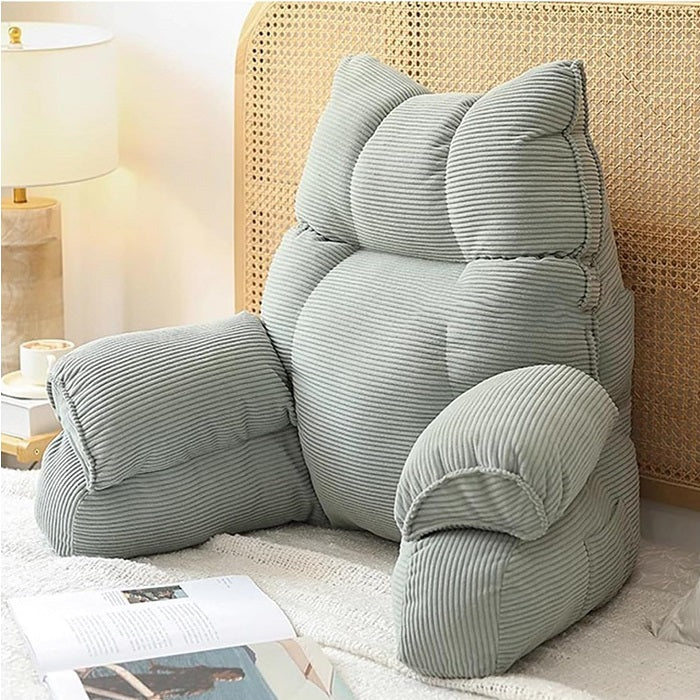 Cushioned bed reading pillow with raised arm supports and ribbed cover