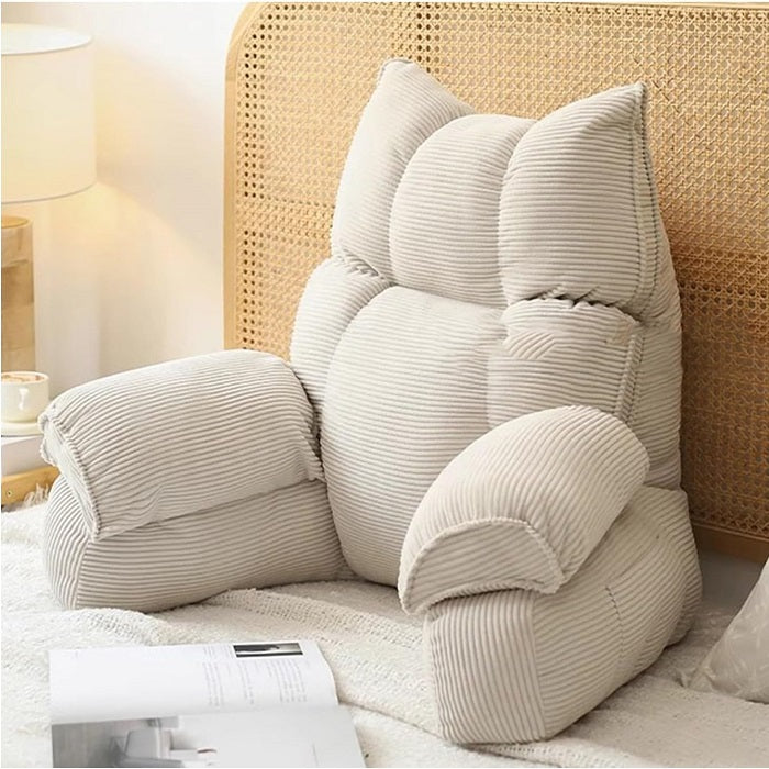 Cushioned bed reading pillow with raised arm supports and ribbed cover