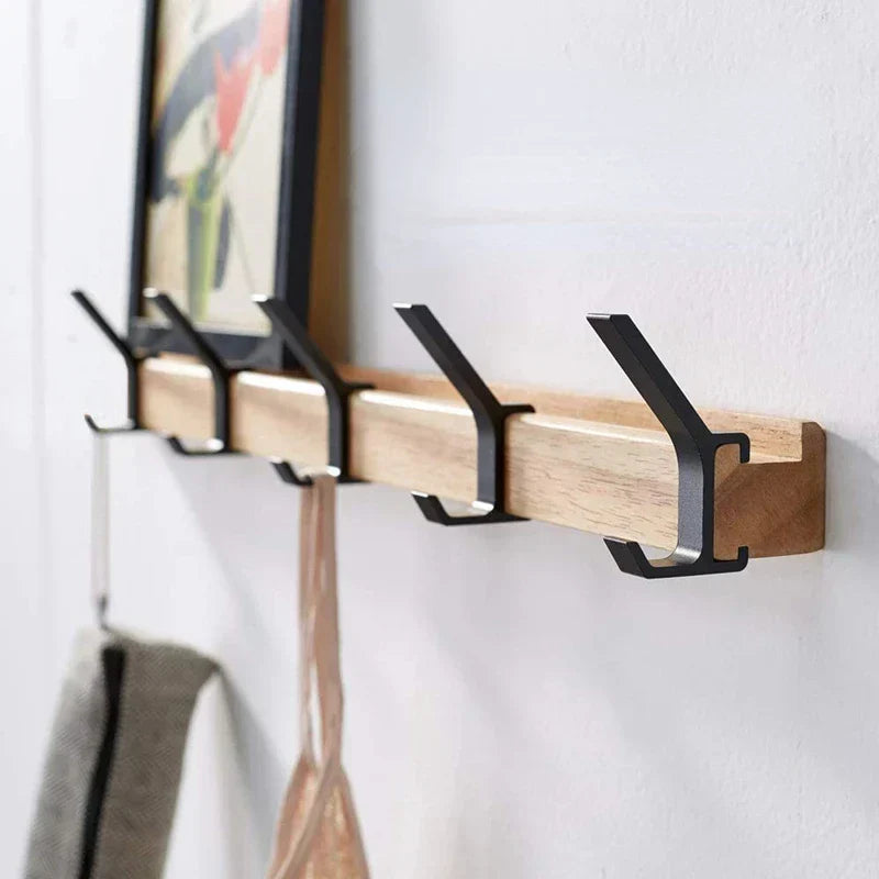Wall-mounted coat rack with black hooks and a wood-effect rail