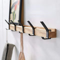 Wall-mounted coat rack with black hooks and a wood-effect rail