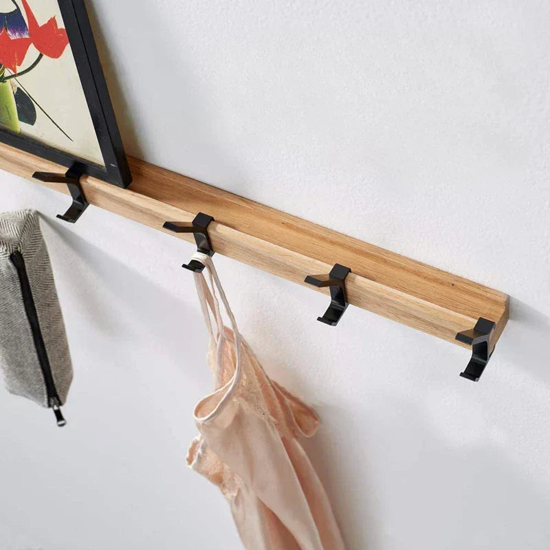 Wall-mounted coat rack with black hooks and a wood-effect rail