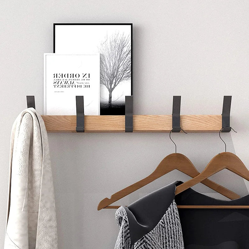 Wall-mounted coat rack with black hooks and a wood-effect rail