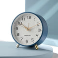 Round Scandinavian analogue table clock with numbered dial and twin feet