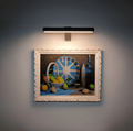 Cordless rotatable LED wall light mounted above framed artwork