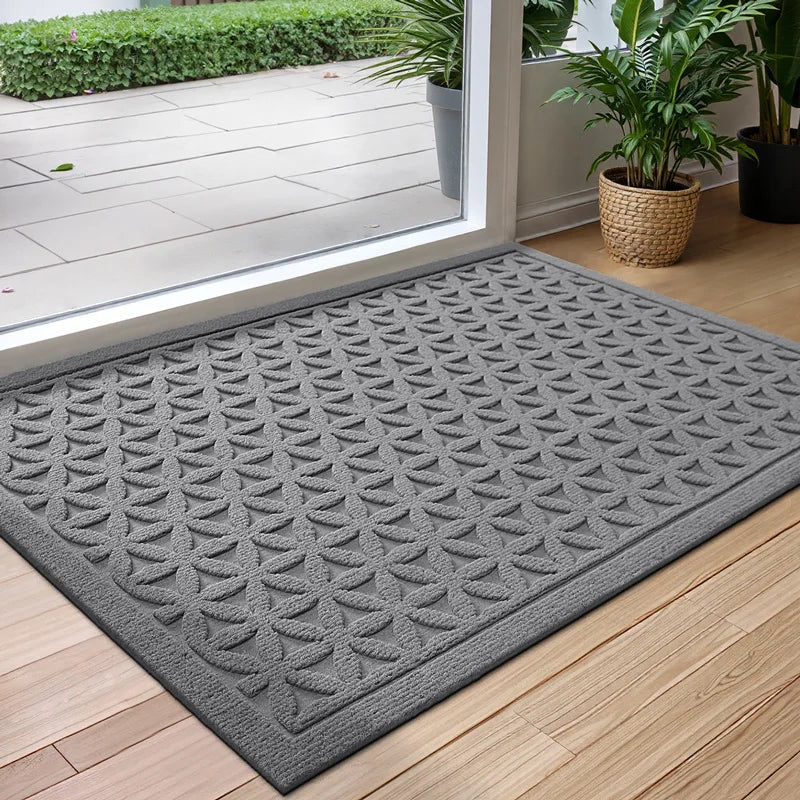 Rectangular geometric door mat with raised grooves by a glass entrance door