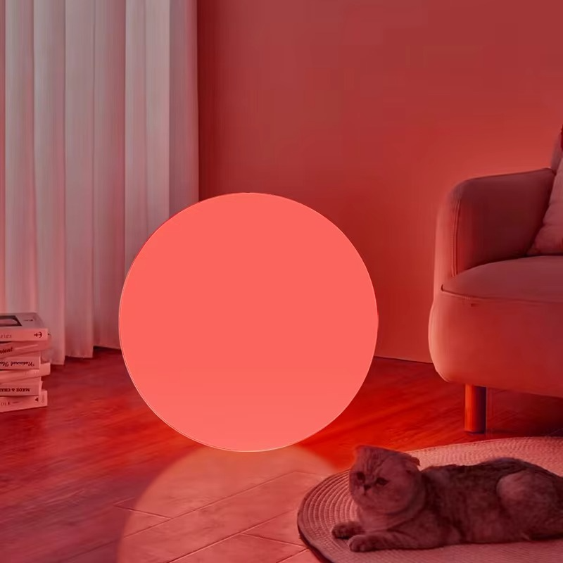 Spherical cordless LED table lamp glowing with colour-changing light