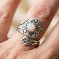 Silver-tone adjustable spoon ring with white opal centre and ornate floral detailing