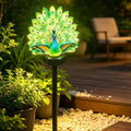 Illuminated peacock solar garden stake light in a planted border