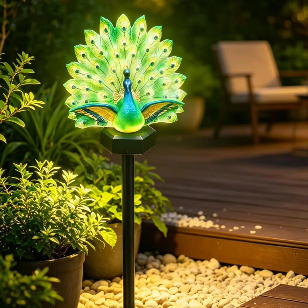 Illuminated peacock solar garden stake light in a planted border