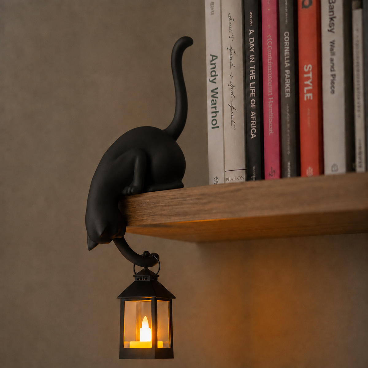 Cat figurine perched on a shelf with a hanging LED lantern